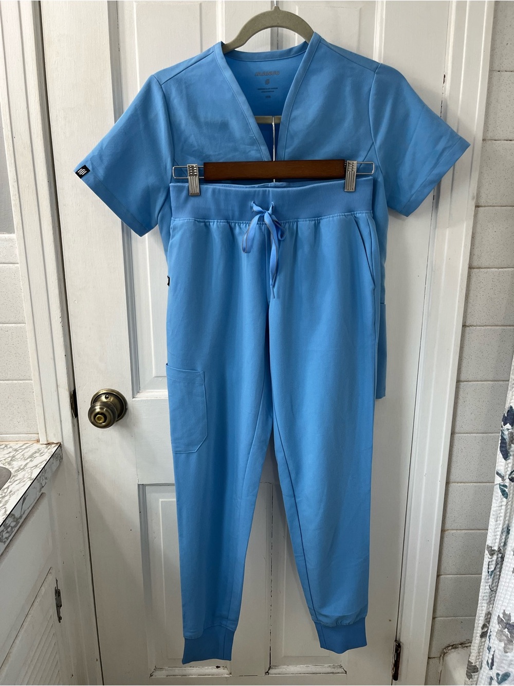 Jaanuu Calix Fit & Flare  Scrub Top with Marching Joggers in Ceil Blue.